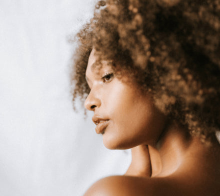 Profile of a woman with natural curly hair against a white background