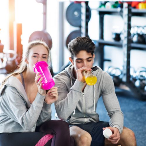 Two people drinking from shaker bottles after a gym session