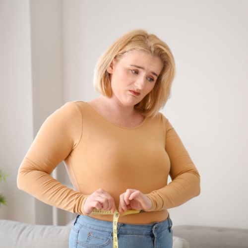 Woman measuring her waist with a tape measure