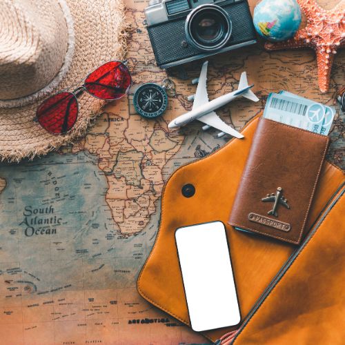 Sun hat, camera, passport and sunglasses laid out on a world map