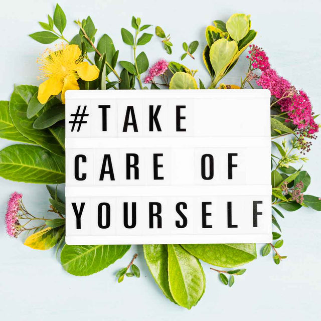 Light box spelling Take Care of Yourself surrounded by leaves and flowers