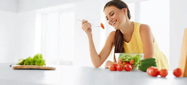 Woman eating a fresh salad at a kitchen counter