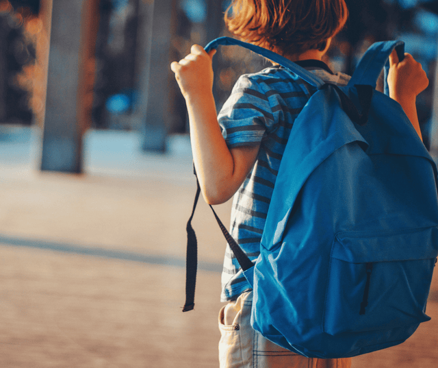 Child with a backpack walking into school