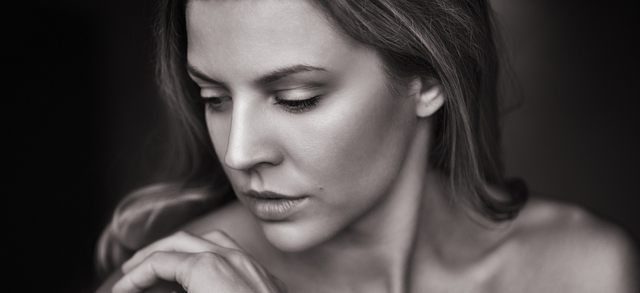 Black and white portrait of a woman looking down, resting her chin on her hand