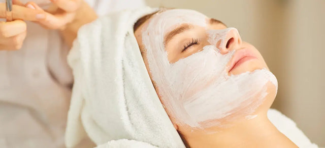 Woman having a white face mask applied at a spa