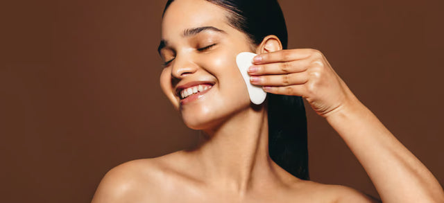 Woman using a gua sha tool on her cheek