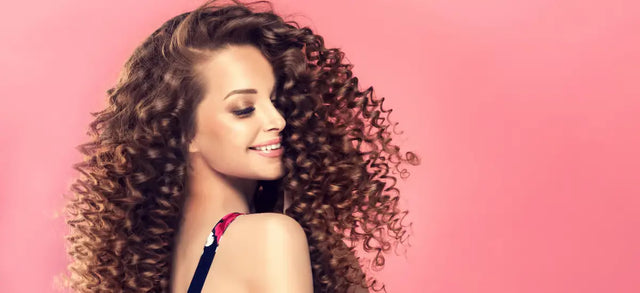 Woman with long curly hair against a pink background