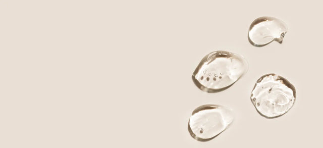 Droplets of clear serum on a beige surface