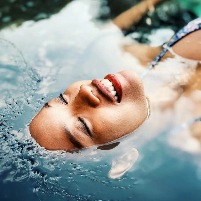 Woman floating on her back in bright blue water