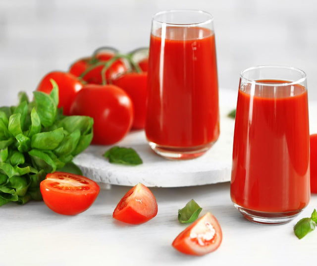 Two glasses of tomato juice with fresh tomatoes and basil