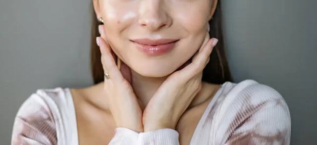 Woman with clear skin resting her hands against her jaw