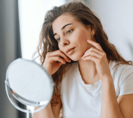 Woman examining her skin in a small round mirror