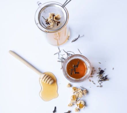 Tea strainer with dried herbs, honey and a jar of ointment